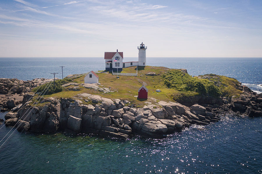 York, ME - View of Nubble Lighthouse Displaying The Ocean Around it on a Sunny Day